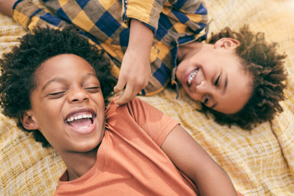 Boy, children and outdoor in park, picnic or top view for love, care or bonding to relax in sunshine. African siblings, kids and happy in garden, comic and funny game for smile, summer and holiday.