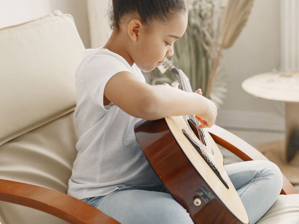 little-girl-with-curly-hair-learning-play-guitar-little-girl-chair